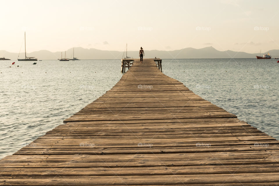 Walking on wooden pier at sunrise 