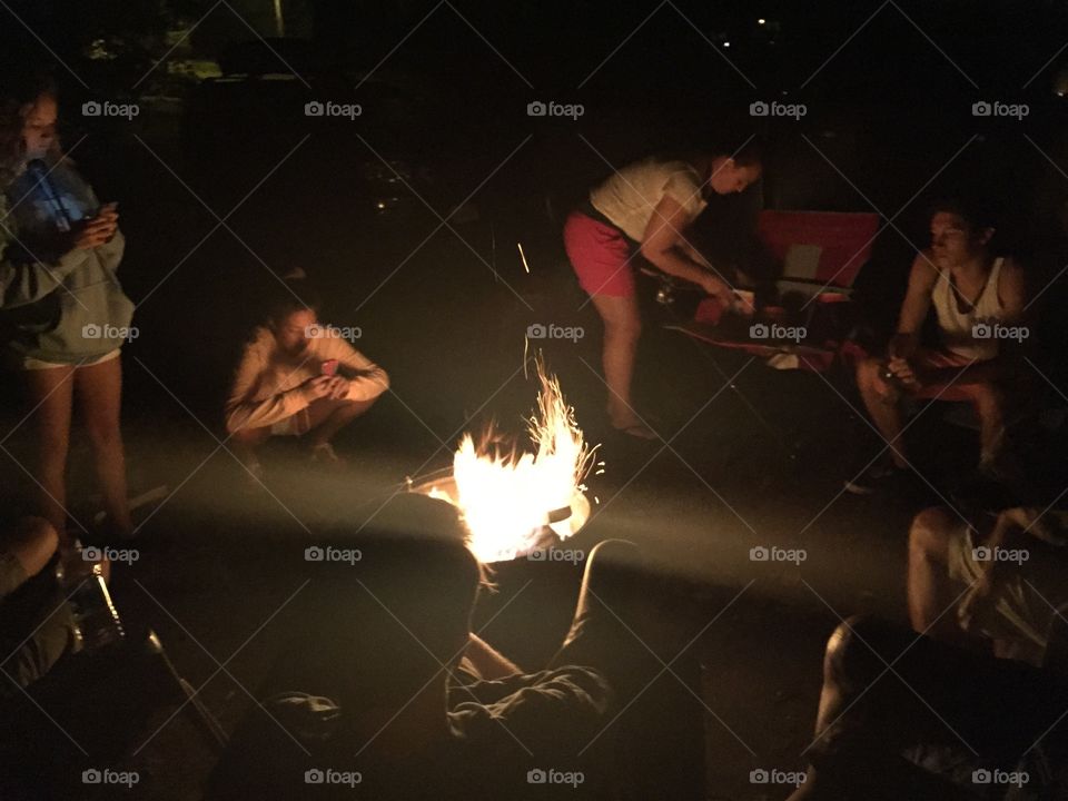 Lit campfire and kids and adults around it.