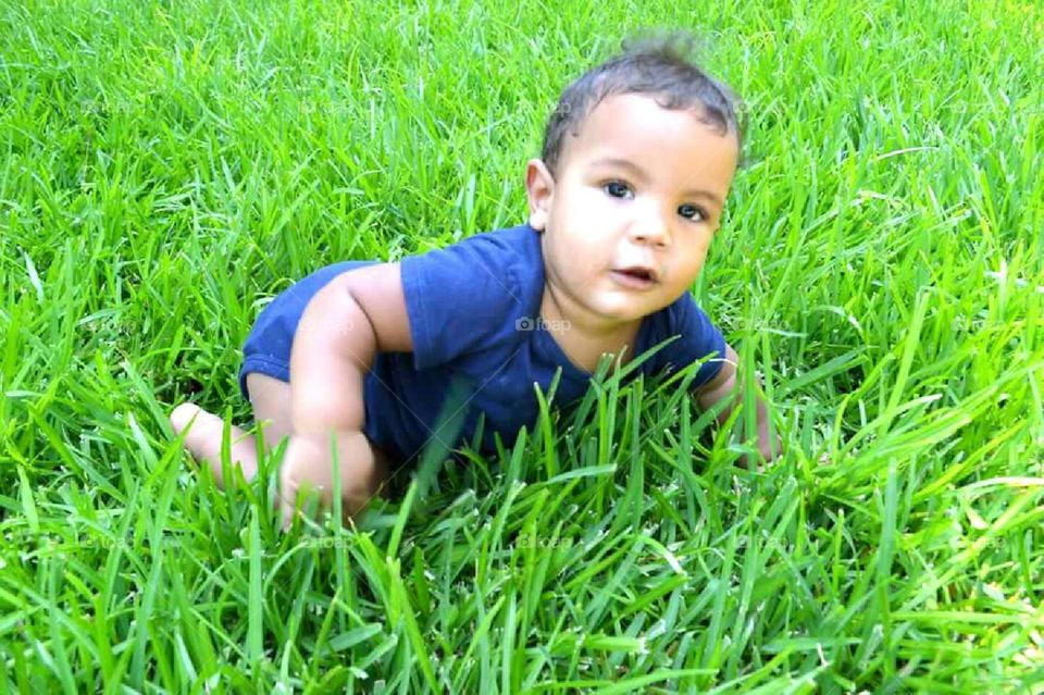 Baby crawling in the green grass.