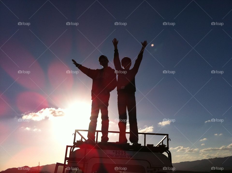 Two Boys Standing on Top of a Van 