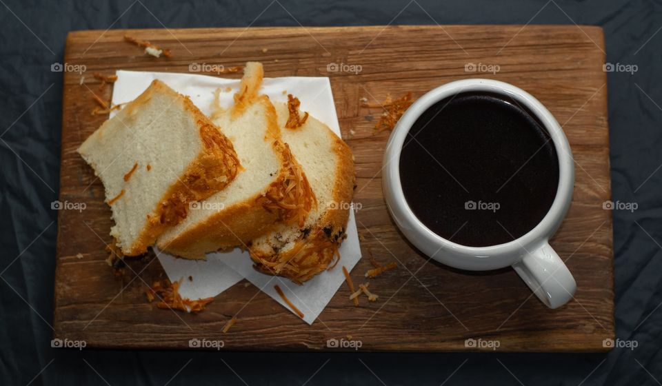 Bread slices with a cup of black coffee on a wooden plate