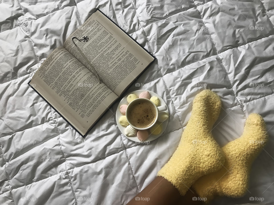 Reading with a cup of coffee in cozy bed 