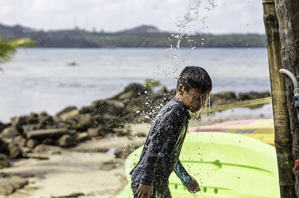 Asian boy wearing a swimsuit and shower Background sea.