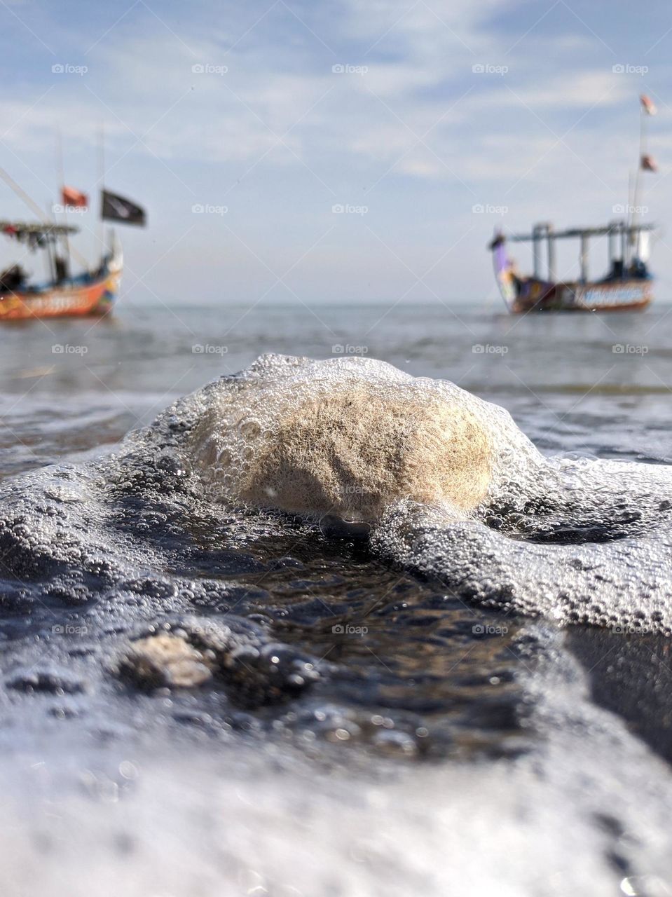 A stone on the beach with boat and sea as background