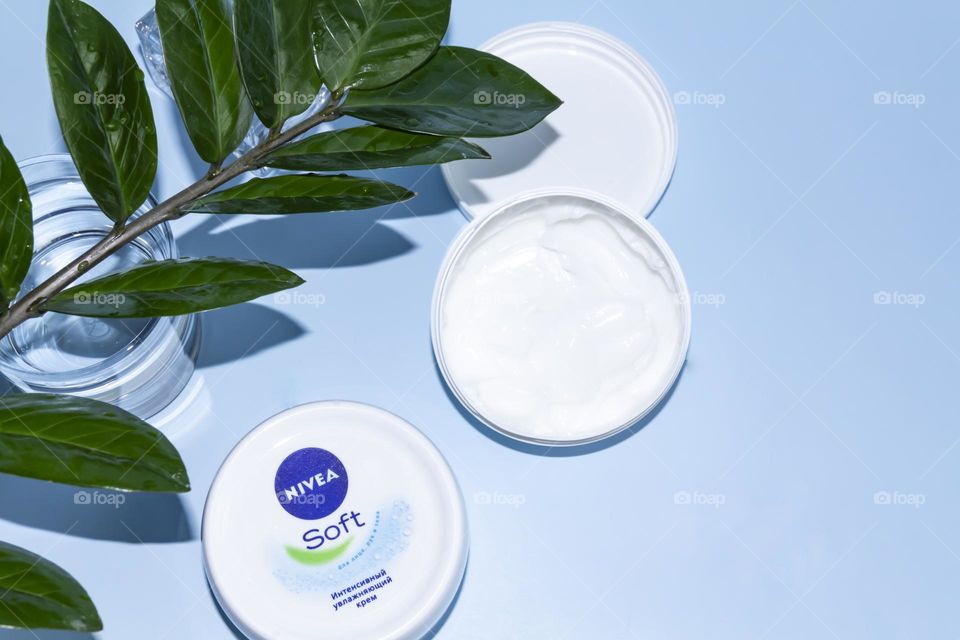 Nivea skin care product on a blue background with a green flower.
