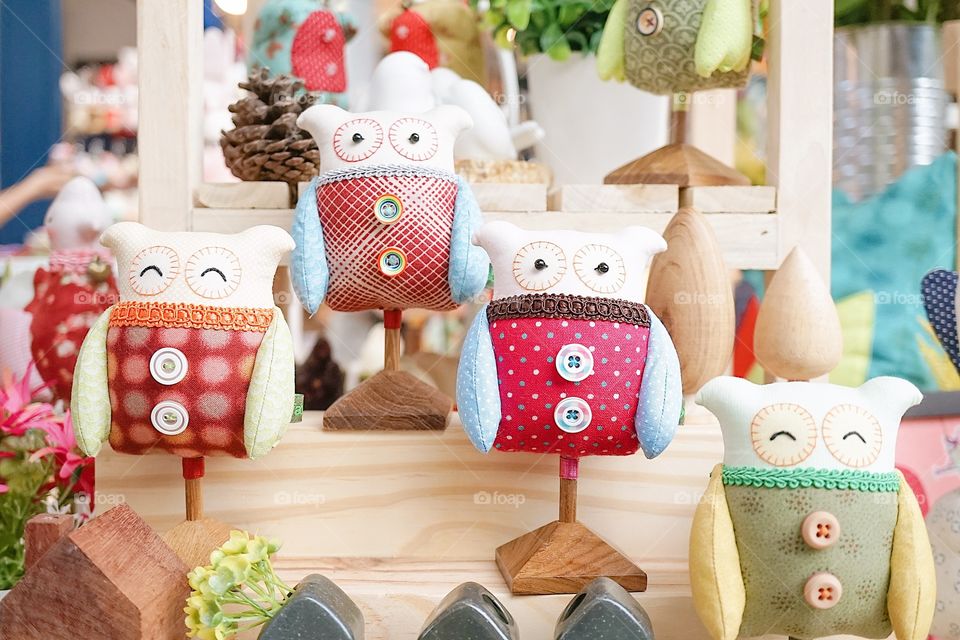 Home decor. Cute home decorative of owls plush with selective focus on the owl in red (the second owl from the right) on display at the weekend market.