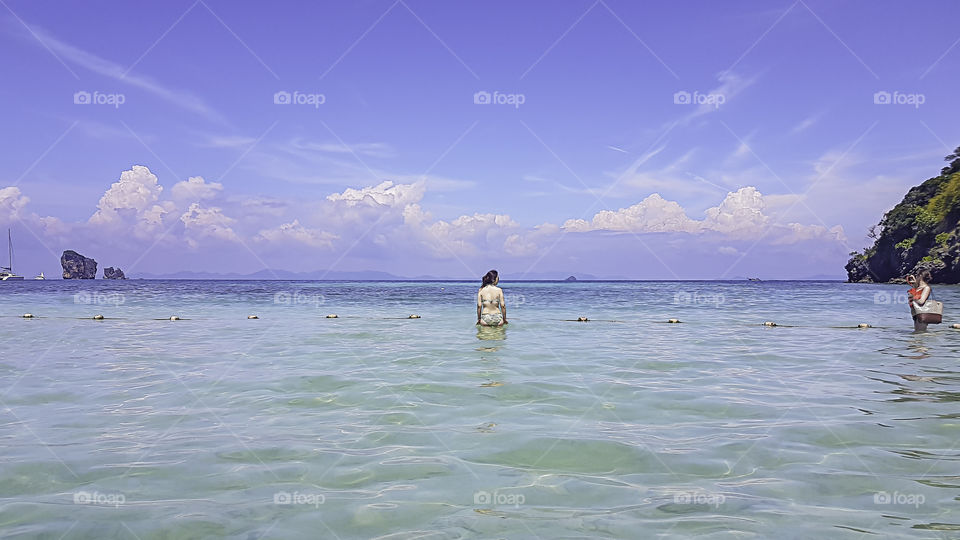 Tourists take photos girl in a sea of clear skies at krabi in Thiland.