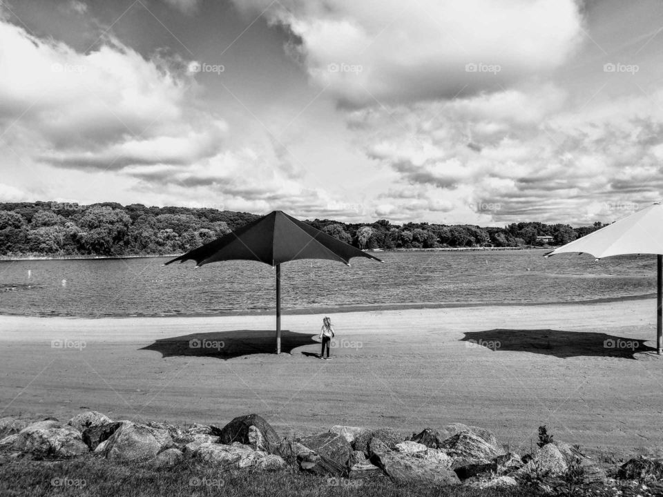 Summer photo of a Lake with umbrellas and shadows on the beach with a child playing  in the sand