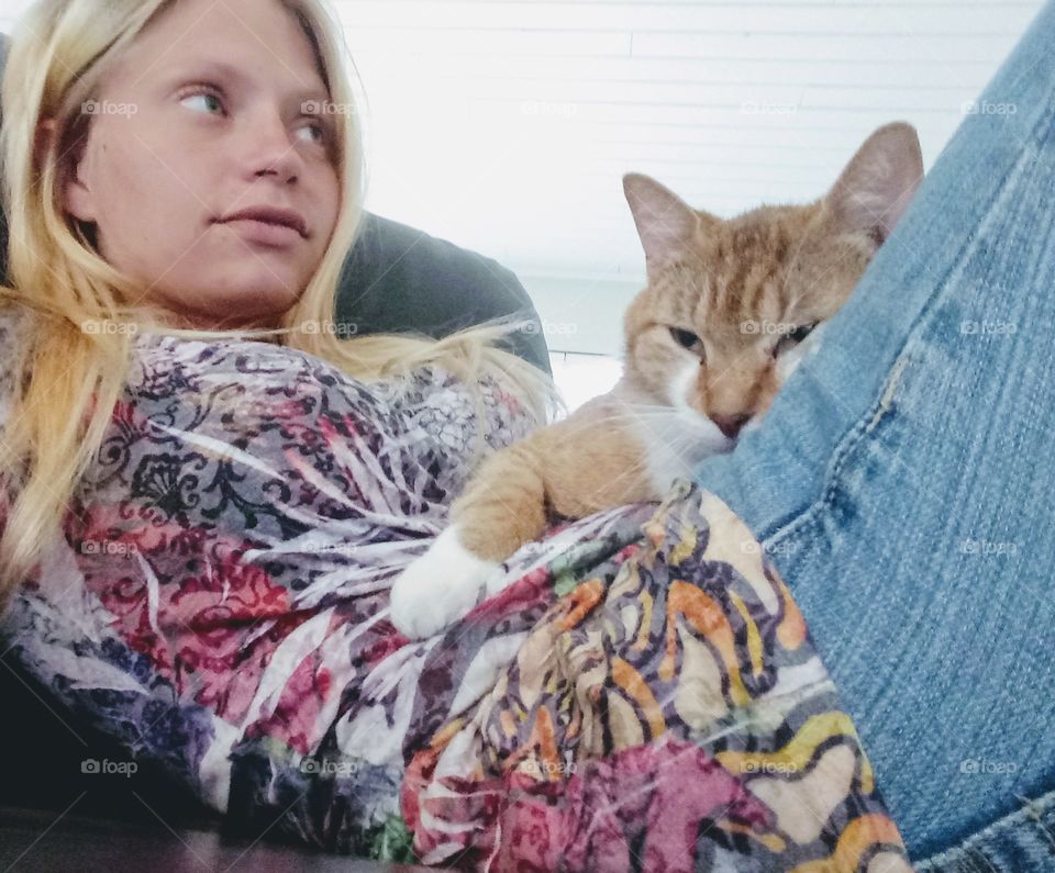 young woman sitting with her pet cat on the sofa