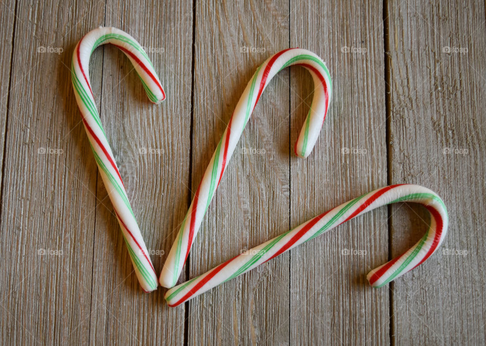 Green and red candy canes on wood background