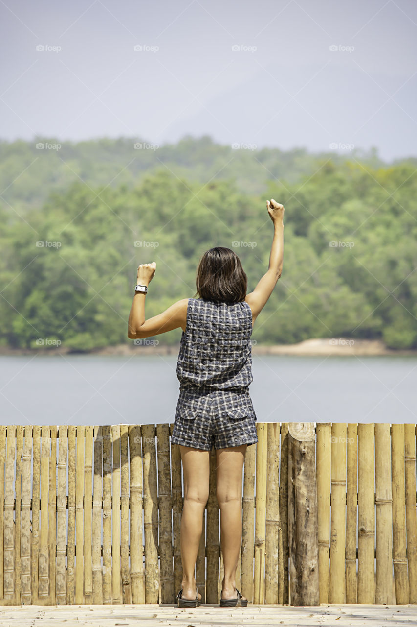 Women raise their arms Background mountains and water at Chakrabongse reservoir , Prachinburi in Thailand.