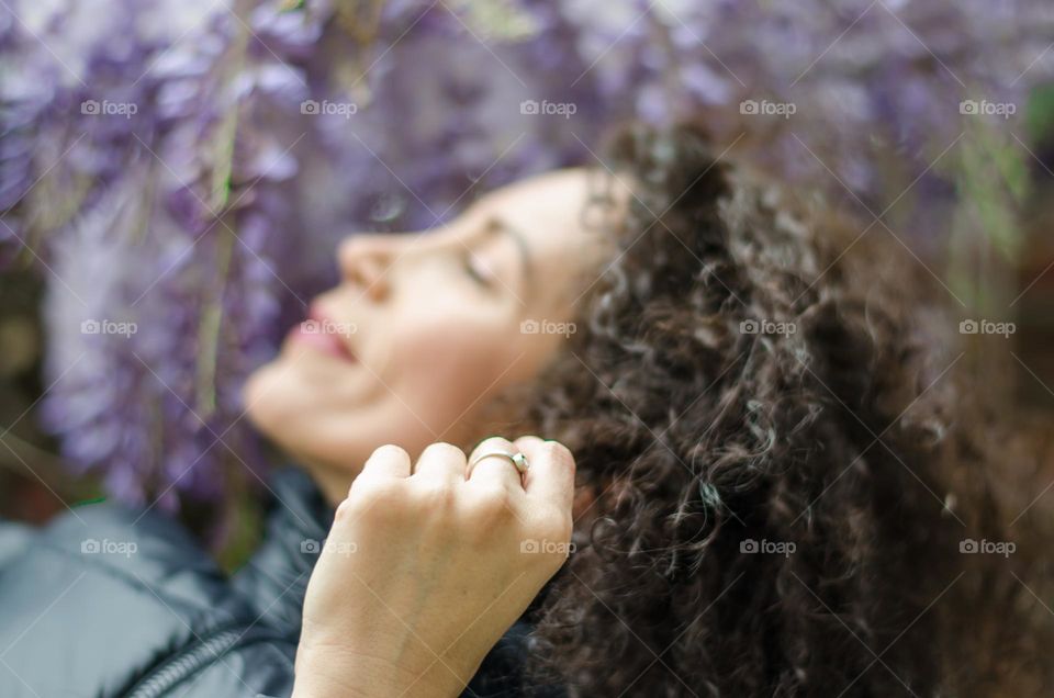 Woman with beautiful curly hair on a background of Wisteria