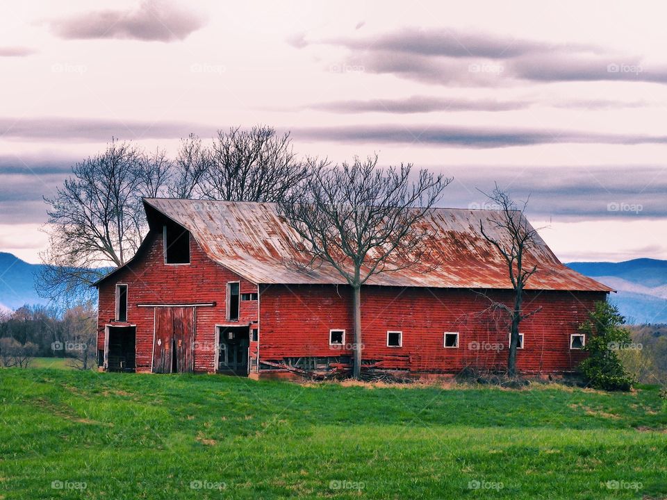Old red barn in country with Blue Ridge Mountains in background. 