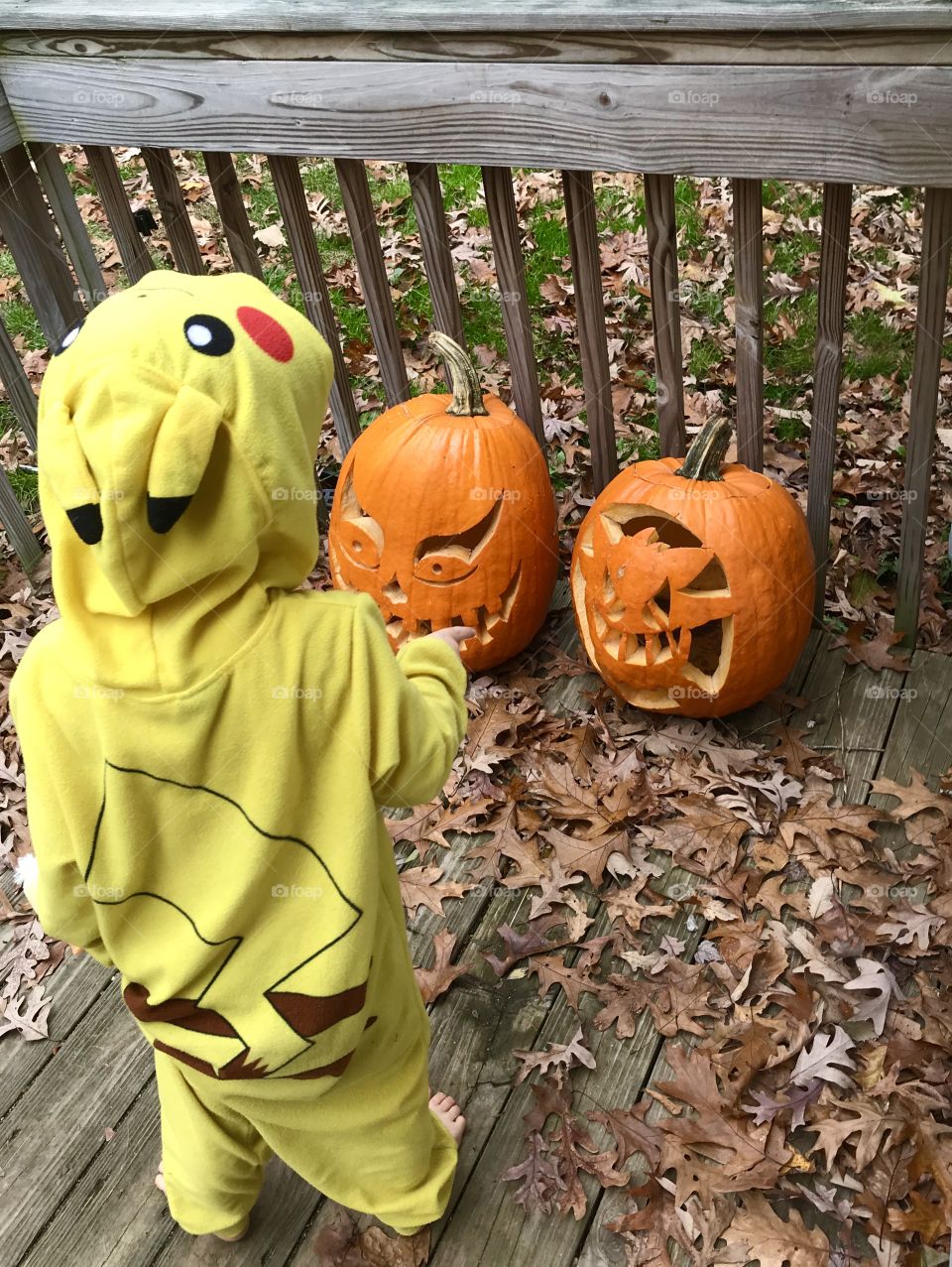 Little boy wearing Pikachu Pajamas admiring his carved pumpkins
