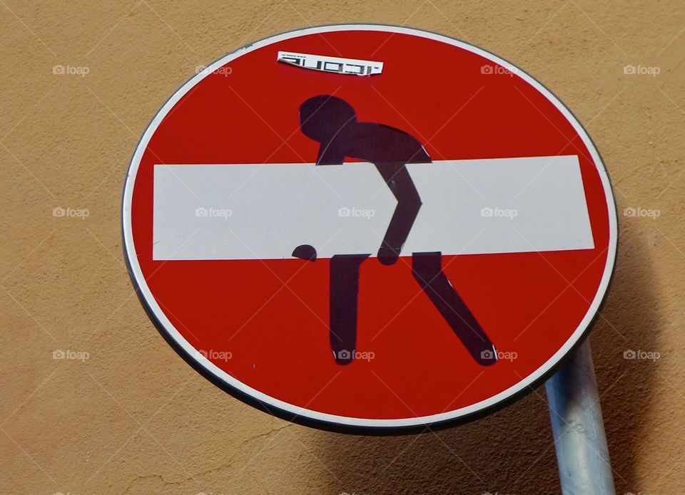 Red metal road sign with funny sticker on it so that it looks like a comic 