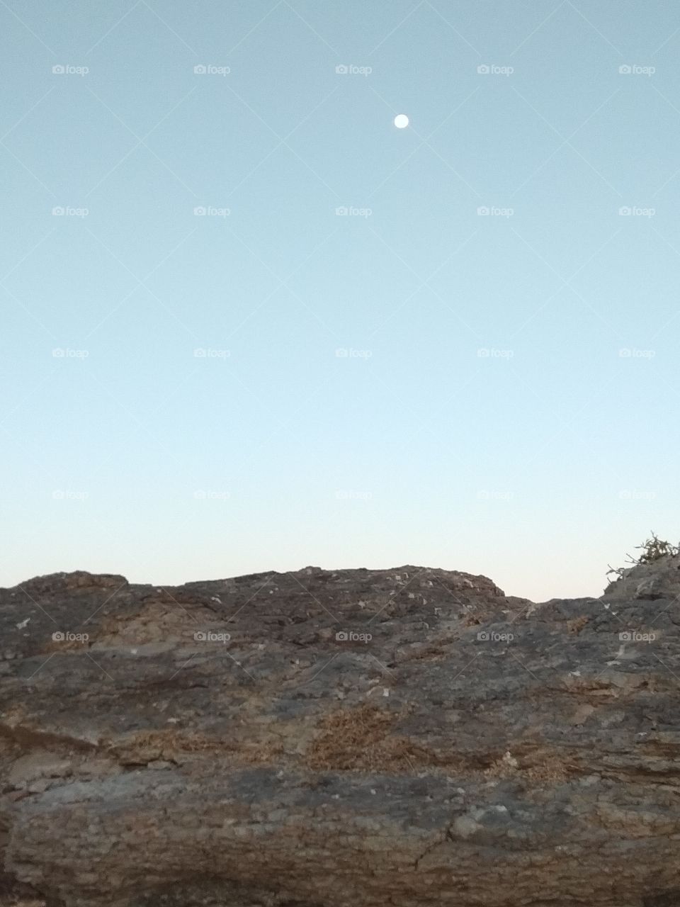Rocks at top of a mountain blue sky and moon waiting sunset