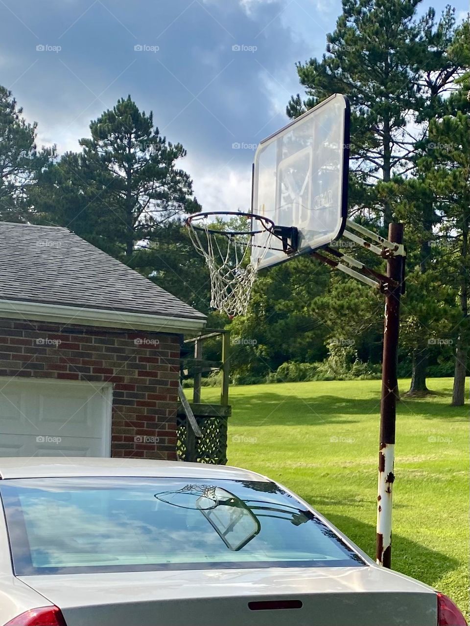 Old basketball hoop reflecting in car’s back window 