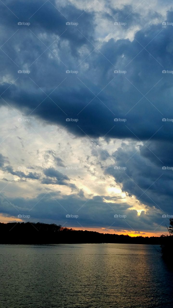 clouds, dark and light, during sunset on lake.