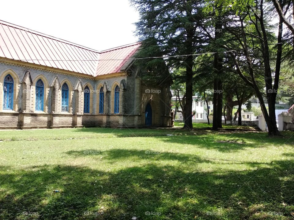 This peaceful photograph captures a church with trees around it, with the warm glow of the sun casting a golden hue on the elegant architecture.