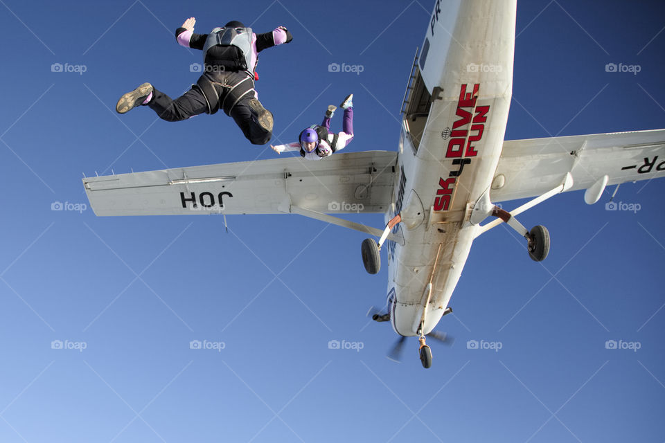 Two skydivers jump from an airplane