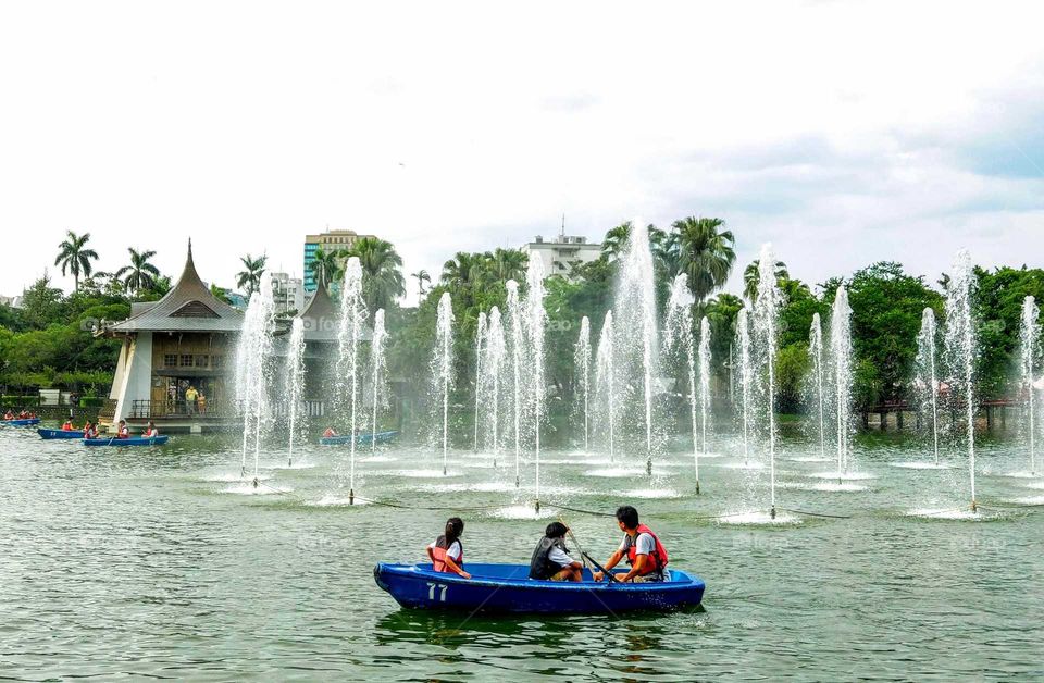 It's summertime!: rowing a boat by the fountain in the park lake that is a good idea to cool off exactly.