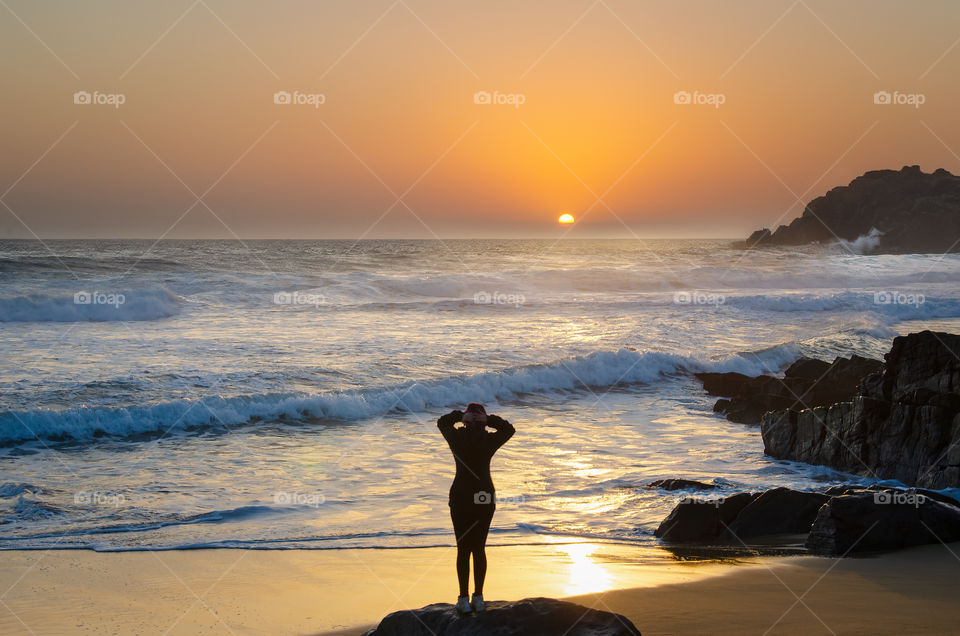 woman watching the sunset on the rocky coast