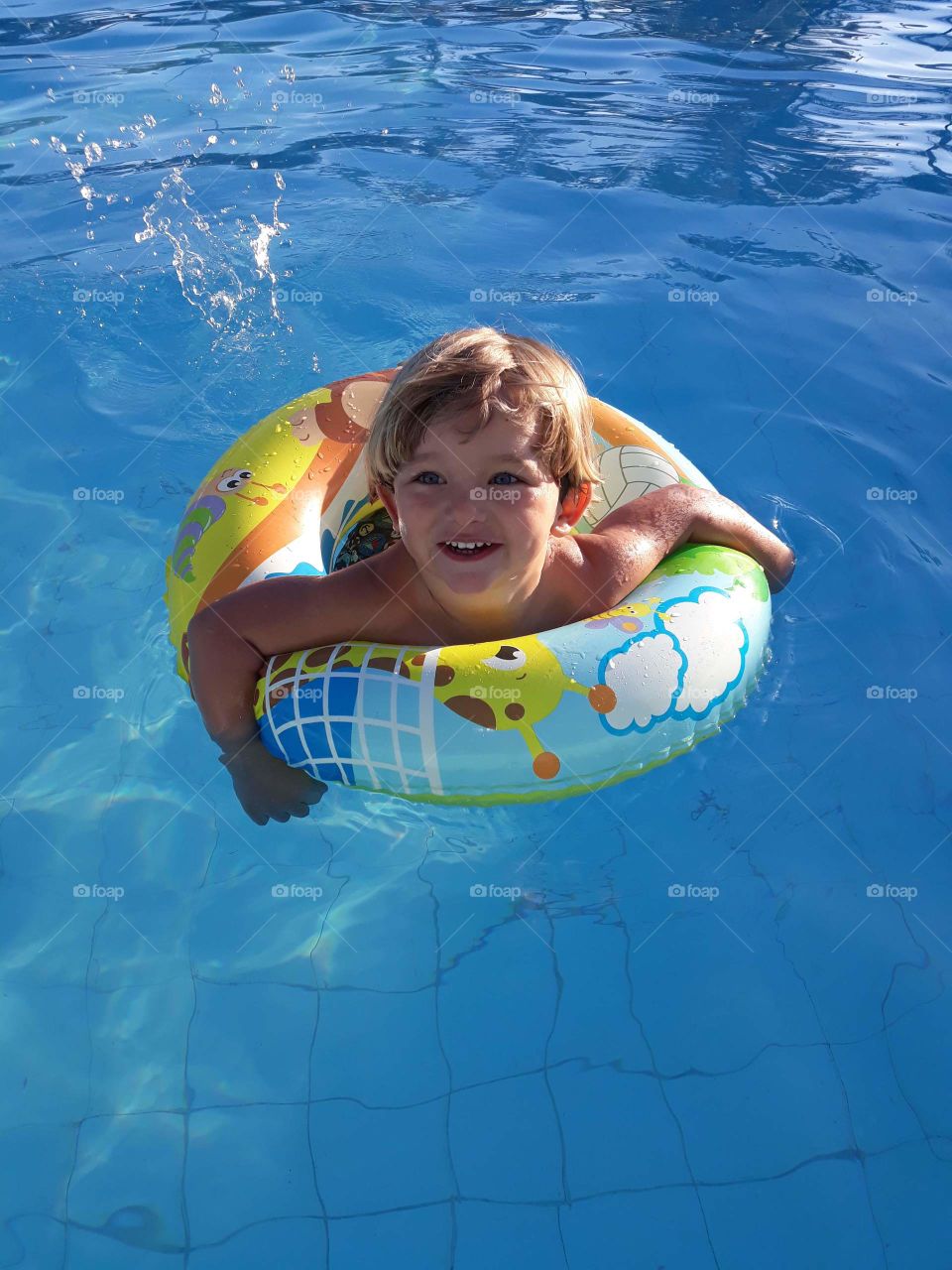 child playing with the float in the blue pool