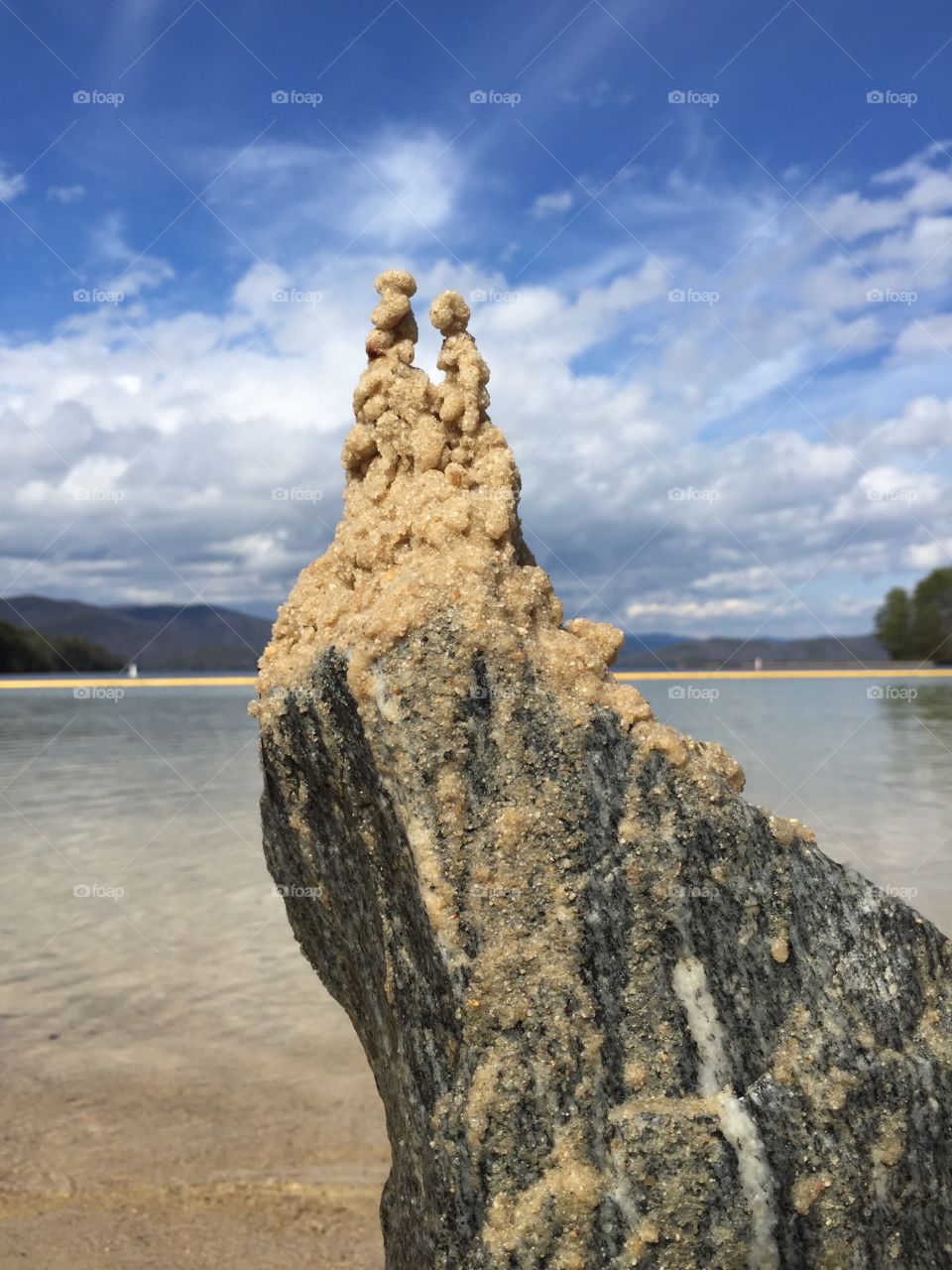 Sandcastle. Sandcastle on a rock in front of a blue lake.