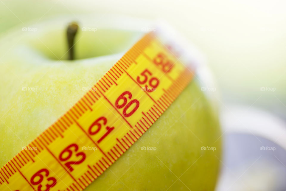 Dieting concept. Green apple with measuring tape. Green apples measured the meter, sports apple