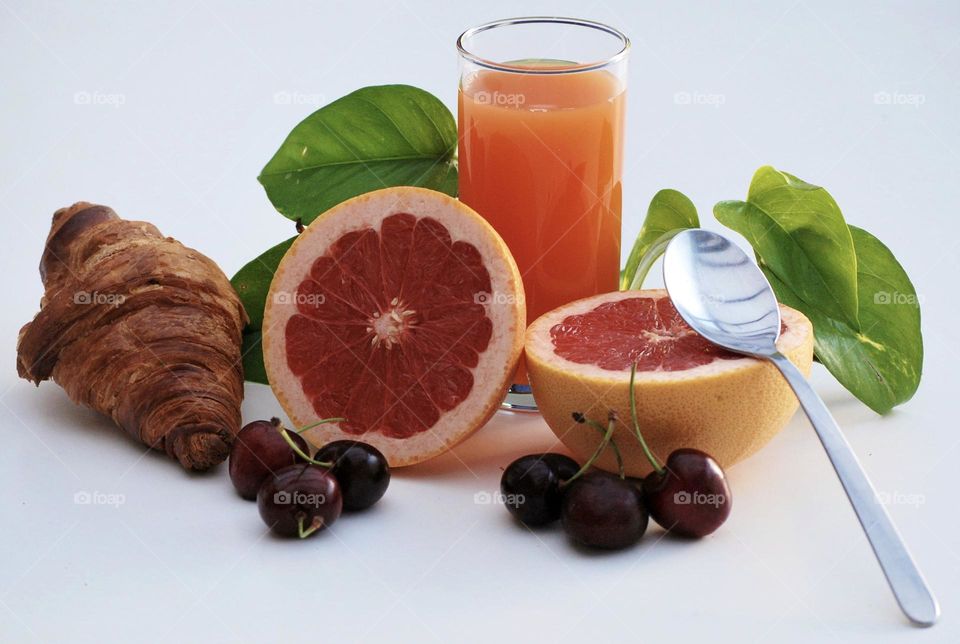 Delicious breakfast with fruit, orange juice, grape fruit, pomelo, cherries, a croissant