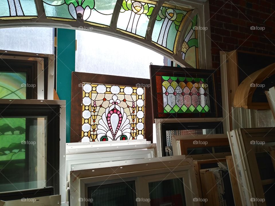 Beautiful stained glass windows in an architectural salvage warehouse showing off their bright colors