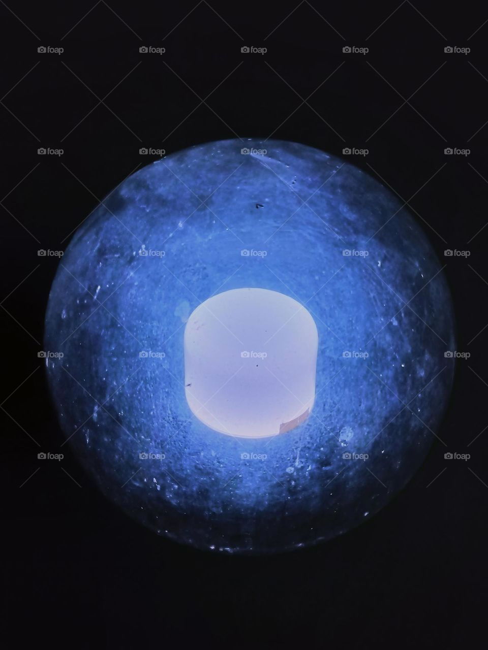 Close-up of round and transparent glass lamp on black background.