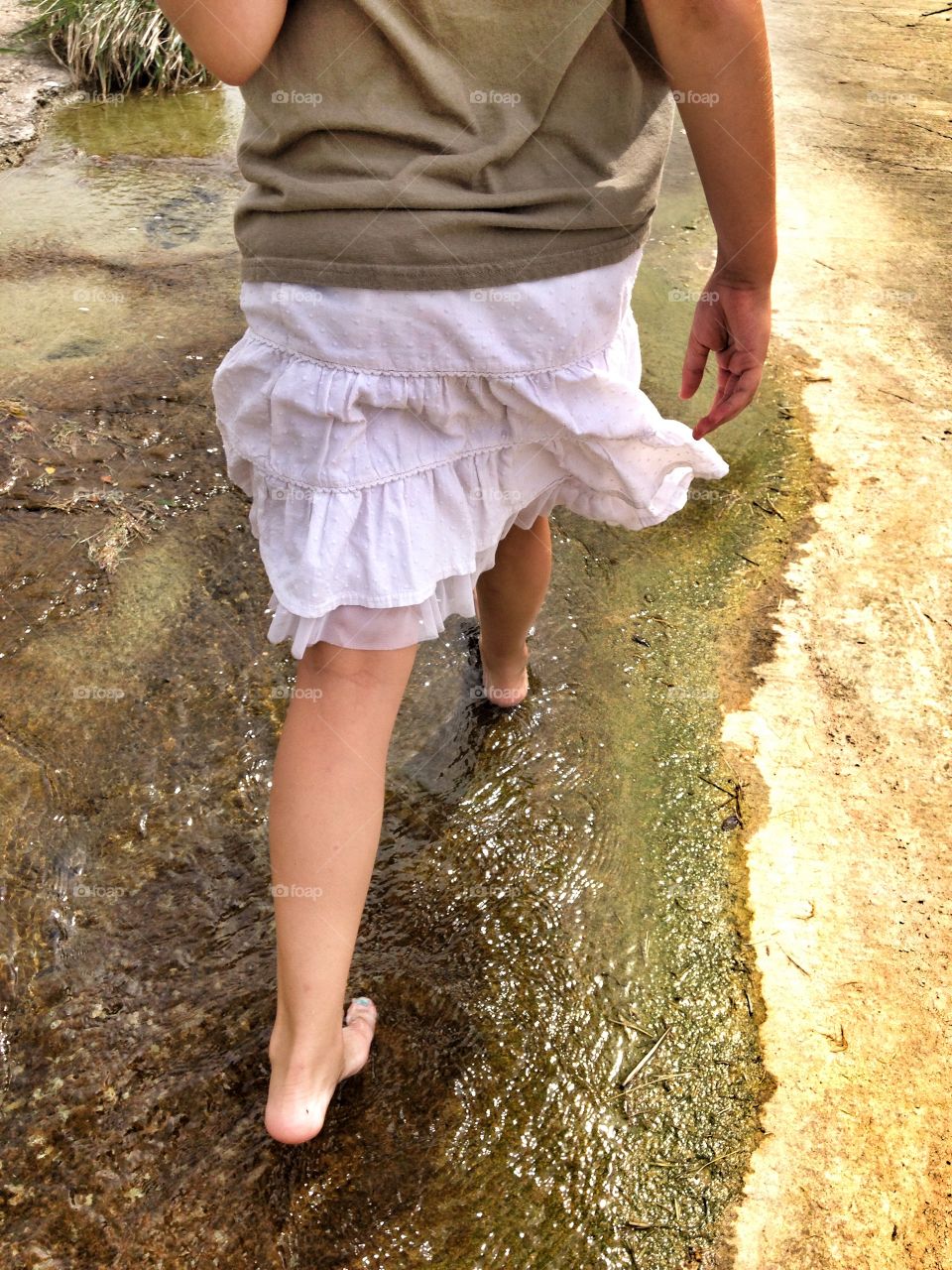 A wet walk. Girl walking in a small stream of water
