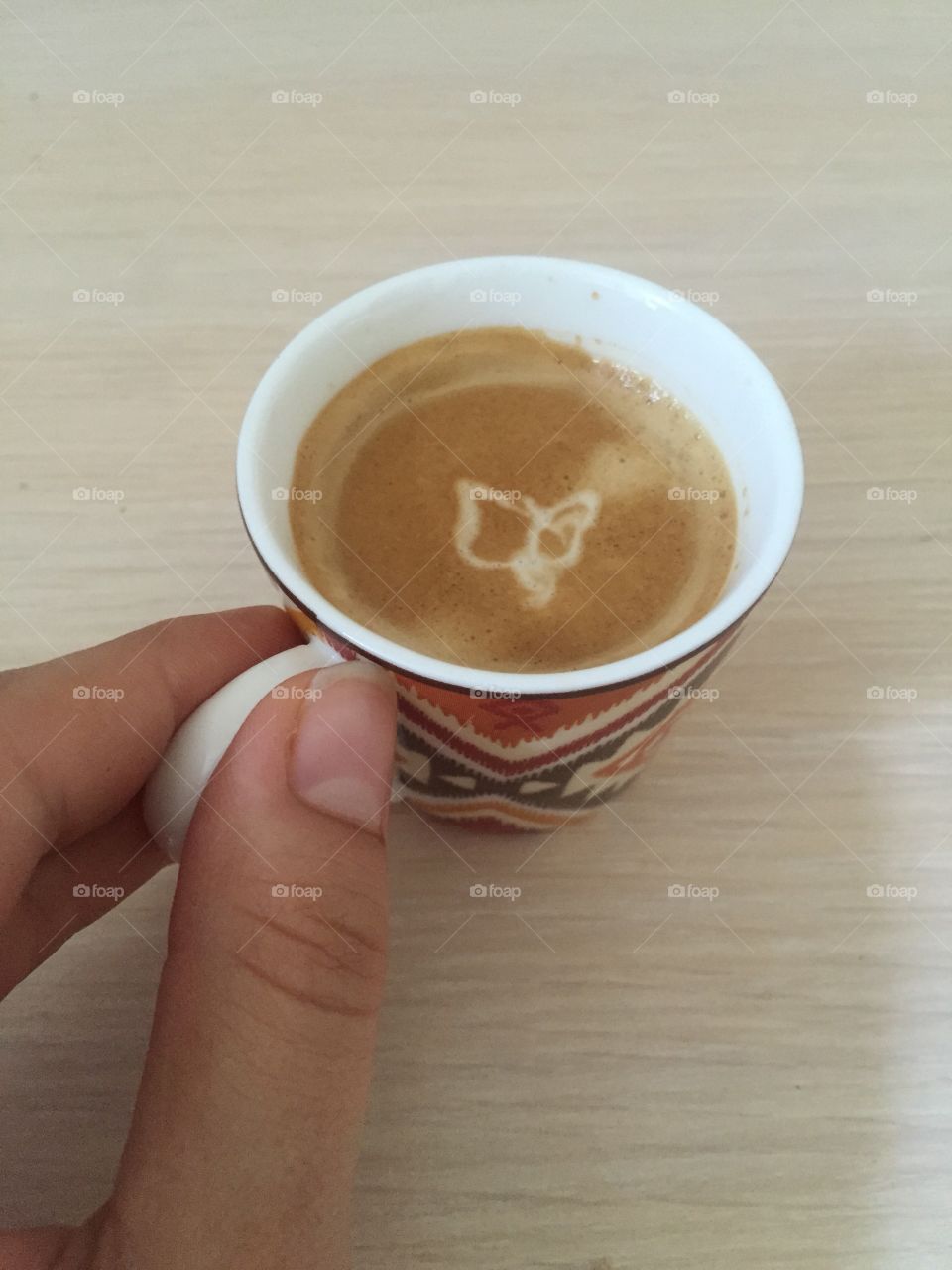 A cup of espresso with a butterfly 