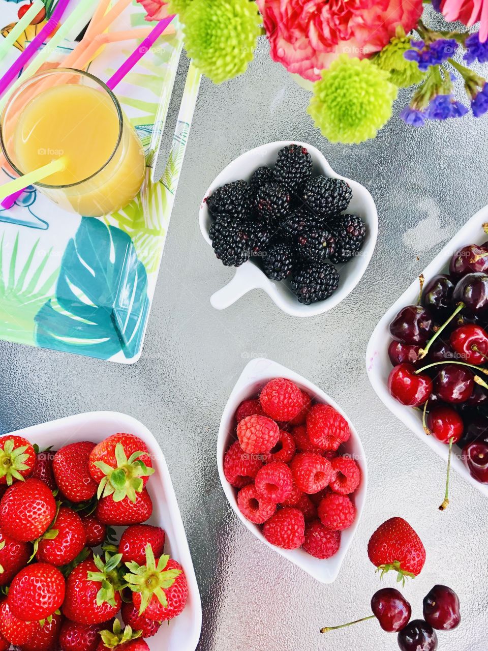 Bowls of fruits, fruit juice and flowers on a patio table