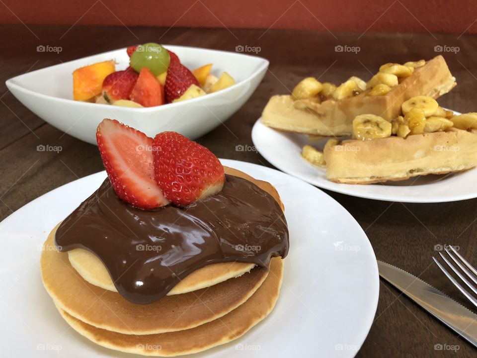 Champions Breakfast. Pankakes with chocolate, Strawberrys, fruir bowl and banana waffle.