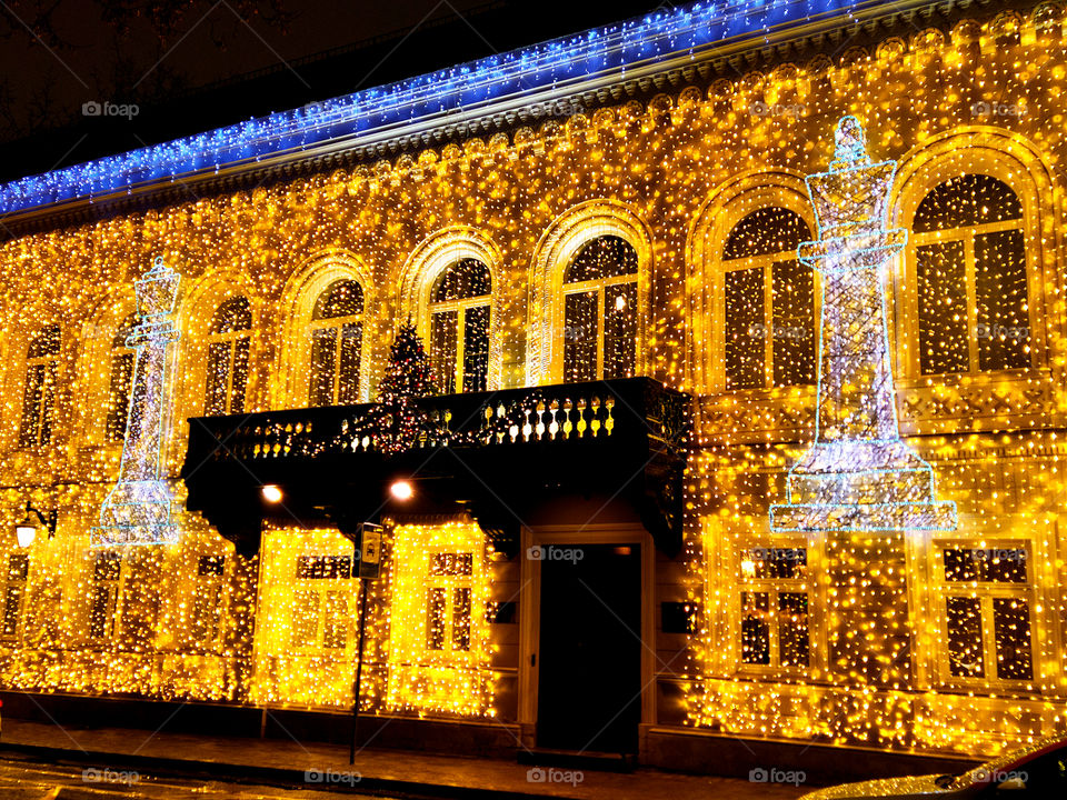 Moscow in the evening.  New Year street decorations.  Ancient house covered with luminous garland and and garland and in the form of chess pieces