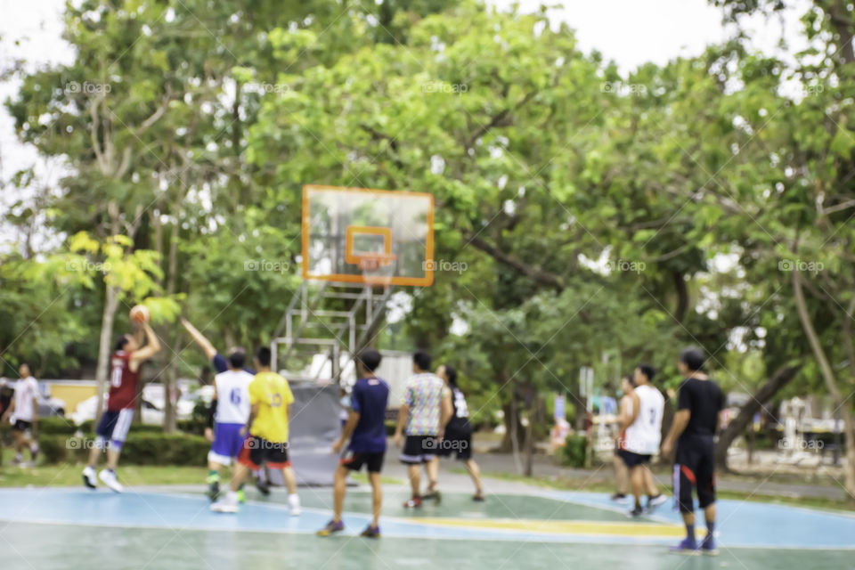 Blurry image of elderly men and teens playing basketball in the morning at BangYai Park , Nonthaburi in Thailand.