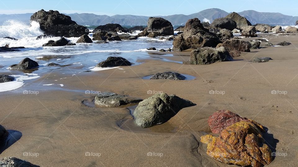 Rocky coast, waves and colored rocks on the beach