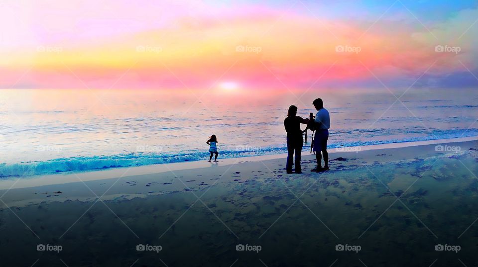 Family at the beach enjoying a very special rainbow colored sunset.