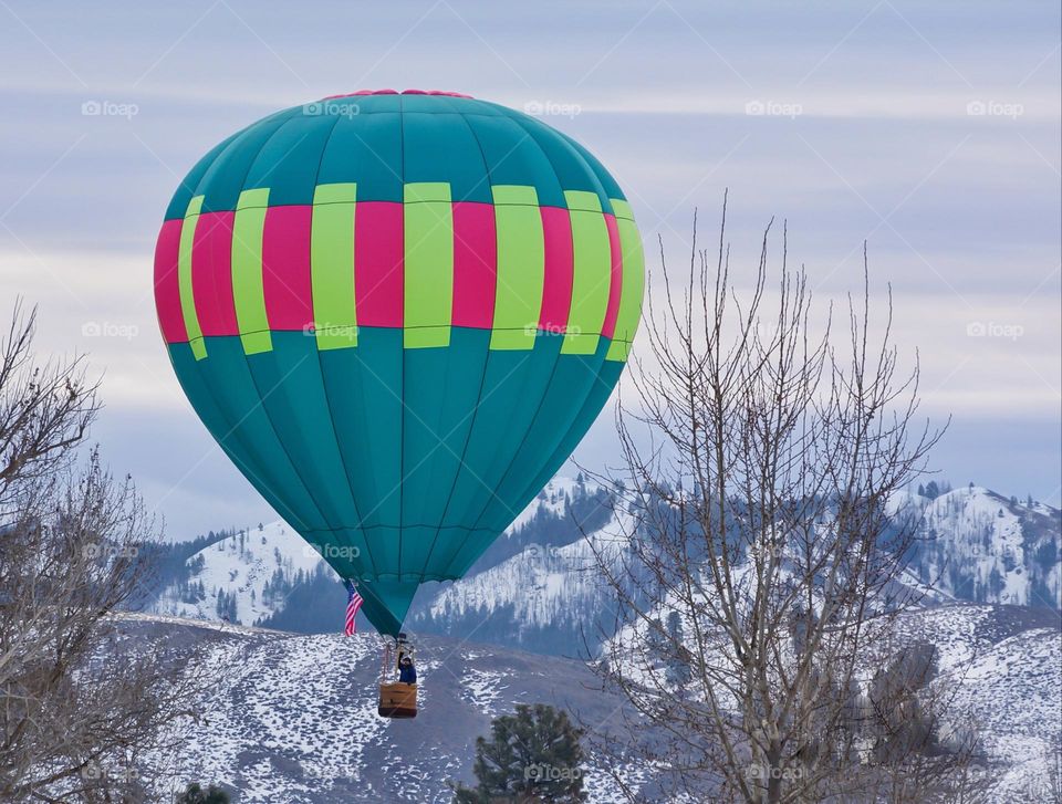 Colorful hot air balloon floating over snow covered mountains 