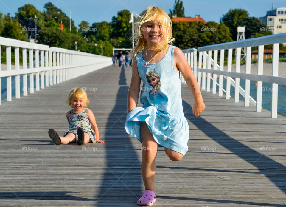 Children playing and running on a bridge by the sea.