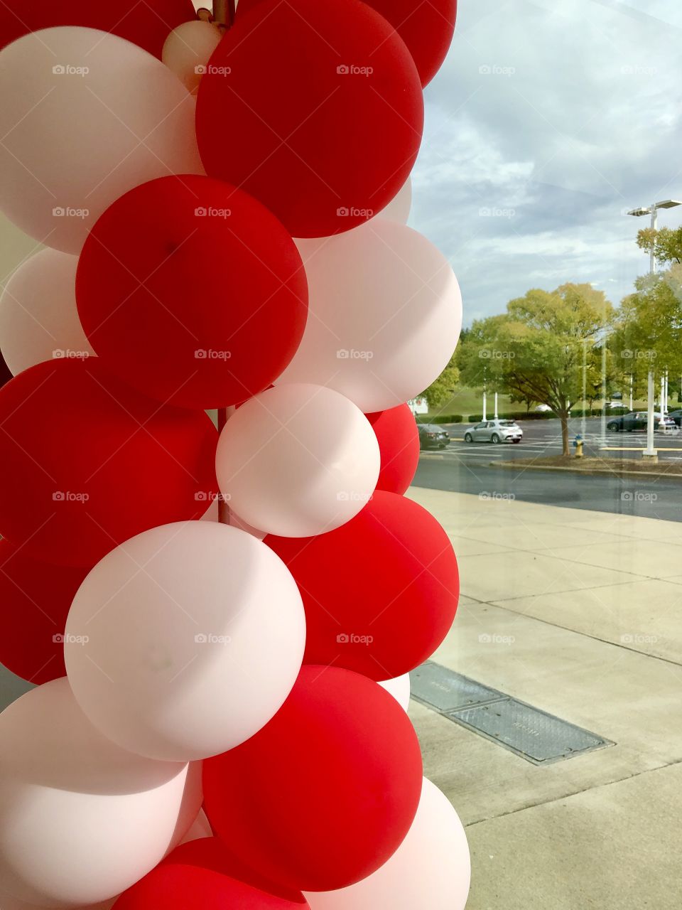 Red and white balloons in foreground inside store window 