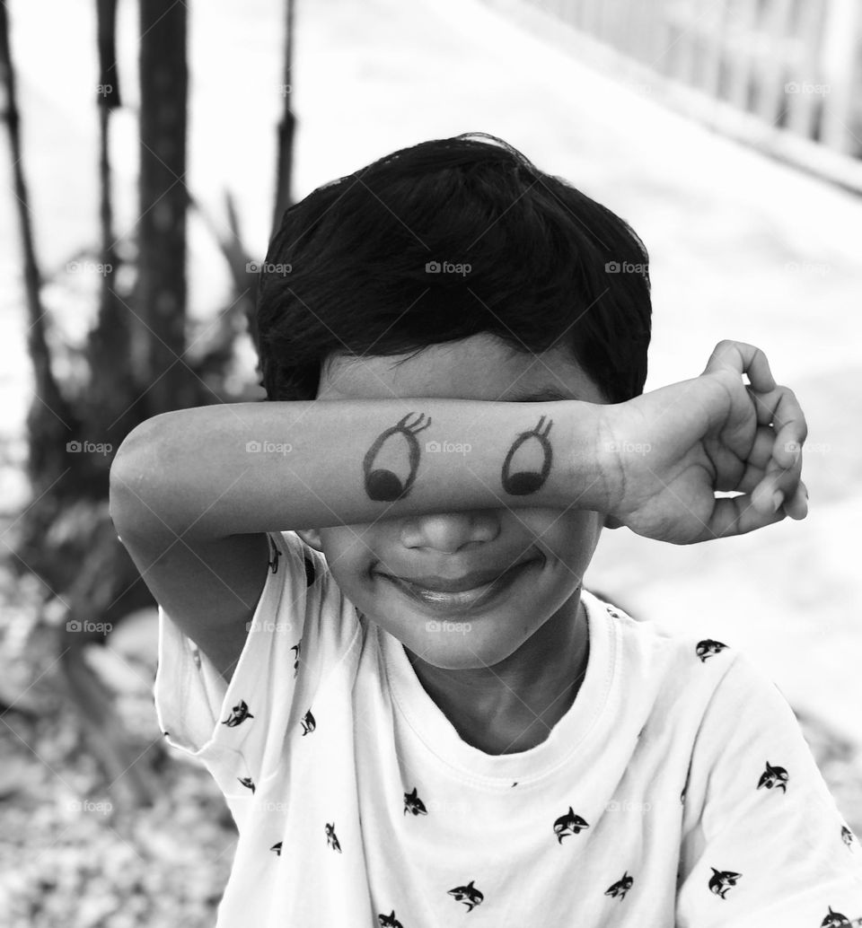 A black and white picture of a funny boy making fun with Mickey eyes 