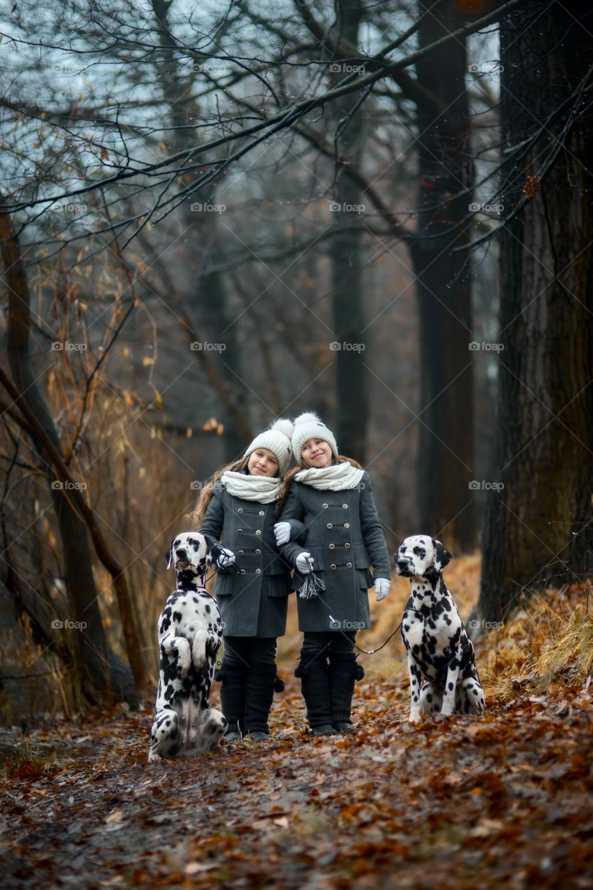 Twins girls in park with Dalmatian dogs 