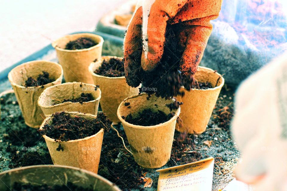 Close up of small plant pots being filled with soil