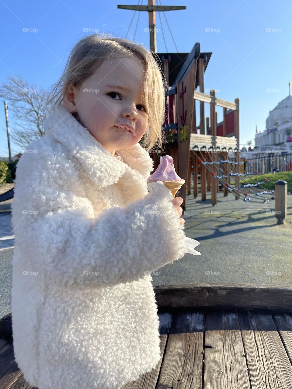 Little girl eating ice cream on playground 