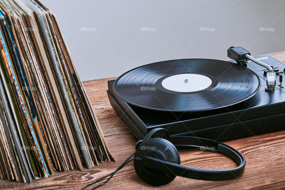 Stack of many black vinyl records, turntable vinyl player and headphones put on the stack. Classic stereo set. Candid people, real moments, authentic situations