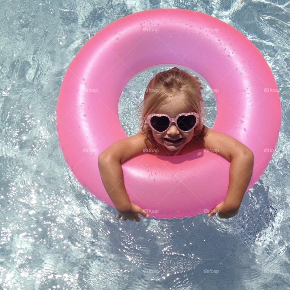 Child at the pool with floatie and sunglasses