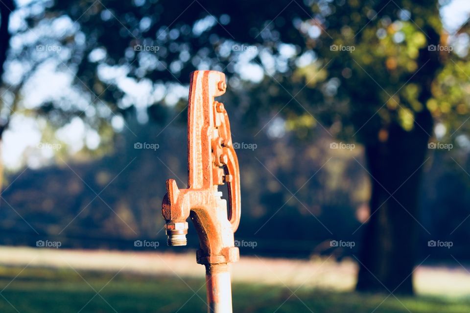 Well-water hydrant against an early autumn country landscape 